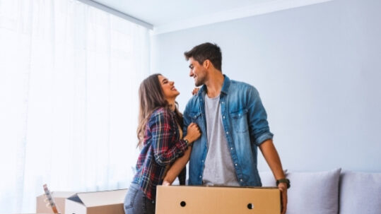 Young couple unpacking cardboard boxes at new home