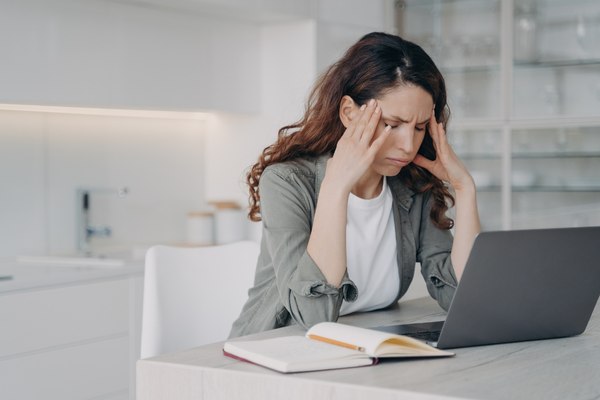 Woman holding head in hands and feeling stressed about financial problems