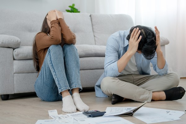 Stressed young couple sitting together and calculating bills at home